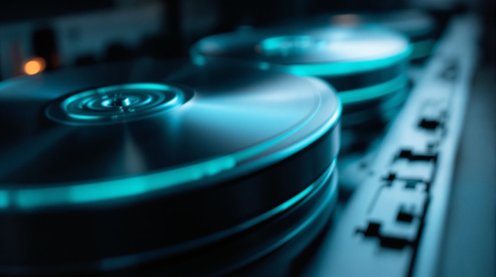 Macro detail of stacked disk platters lit in cool cyan against graphite, with open negative space to the right