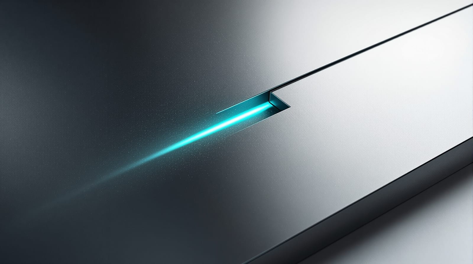 Machined graphite plate split by a narrow seam with a thin line of cyan light escaping, open space at right